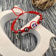 a pair of red string bracelets sitting on top of a wooden letter shaped object