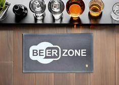 a sign that says beer zone next to some glasses on a table with a plant