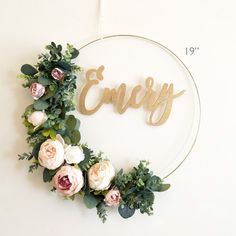 a floral wreath with the word enjoy spelled in cursive wood letters on a white wall