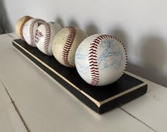 three baseballs sitting on top of a wooden shelf next to each other with autographs written on them