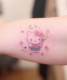 a hello kitty tattoo on the arm with stars and a moon above her left shoulder