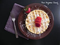 a plate topped with waffles covered in powdered sugar and sliced strawberries