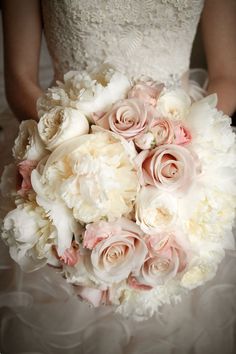 a bride holding a bouquet of white and pink flowers