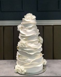 a white wedding cake with ruffles and flowers