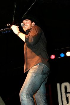 a man standing on top of a stage holding a microphone in his right hand and singing