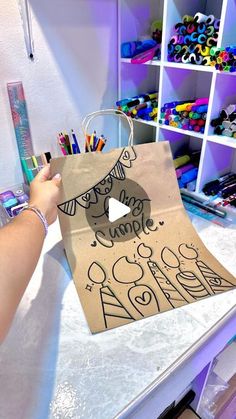 a person holding a paper bag with an image on it and some crayons in the background