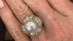 This magnificent cocktail ring is centered with one (1), post set, cultured South Sea pearl. The pearl tops a domed setting is bead set sixty-four (64), bead set, round brilliant cut diamonds. The ring has a split shank design and is accented with seven (7), bead set, round brilliant cut diamonds on each side. The ring measures 21.7mm at the top, rises 18.6mm above the finger, tapering to 2.4mm wide and 1.1mm thick at the base of the shank. The ring is currently size 7. Elegant White Domed Rings, Elegant White Domed Jewelry, Luxury Oval Pearl Ring, Luxury High Luster Pearl Ring For Formal Occasions, Luxury Domed Jewelry For Formal Occasions, Luxury Domed Jewelry For Weddings, Luxury Domed Wedding Jewelry, Luxury Pearl Drop Ring For Formal Occasions, Luxury Domed Jewelry With Brilliant Cut