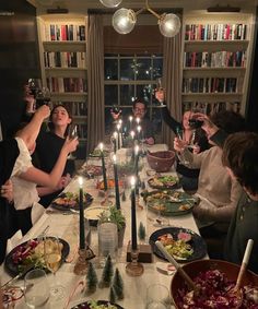 a group of people sitting around a table with food and candles in front of them