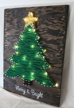 a string wrapped christmas tree is displayed on a wooden plaque with lights and a star