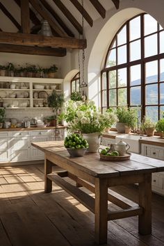 a wooden table sitting in front of a window filled with potted plants and greenery