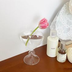 a glass vase with a pink flower in it next to other items on a table