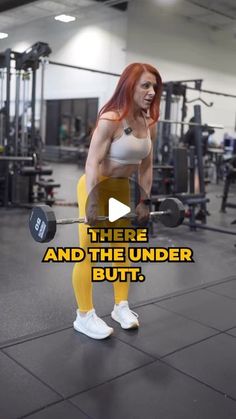 a woman with red hair and yellow pants is lifting a barbell in the gym