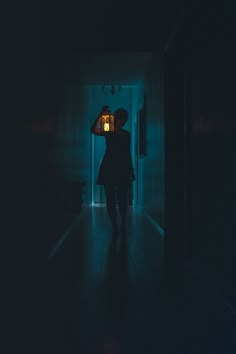 a woman standing in a dark hallway with her back to the camera