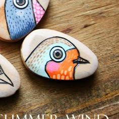 three painted rocks sitting on top of a wooden table with the words summer wind written below them