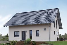 a white house with a black roof in the grass