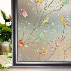 there is a framed painting with birds on the tree branches and flowers in front of it