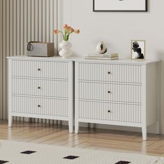 a white dresser with two vases on top of it next to a painting and pictures