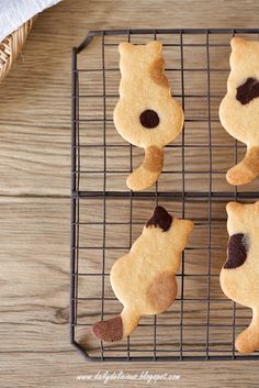 four cookies shaped like cats on a cooling rack with one cookie in the shape of a cat