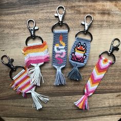 four keychains with different designs on them sitting on a wooden table next to each other