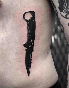 a black knife tattoo on the side of a woman's ribcage is shown