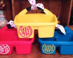 three personalized plastic containers with monogrammed bows on the handles and bottoms