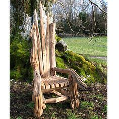 a wooden chair made out of logs sitting in the grass next to a tree stump