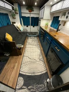 the interior of a camper with blue curtains and wood flooring