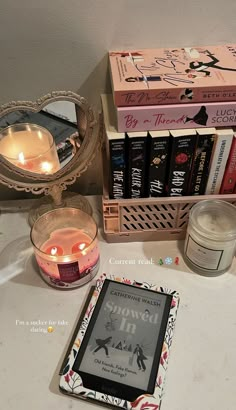 a table topped with books and candles next to a mirror