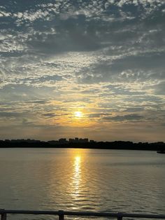 the sun is setting over the water with clouds in the sky