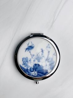 a compact mirror with blue and white flowers on it