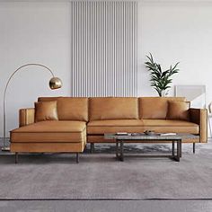 a living room with a couch, coffee table and lamp on the wall next to it