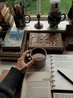 a person sitting at a table with books and a cup of coffee in front of them