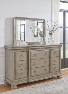 a dresser with a mirror and vase on top