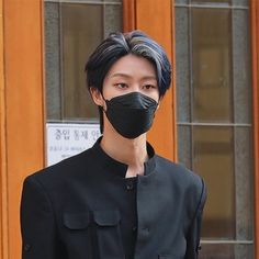 a man wearing a black face mask standing in front of a door