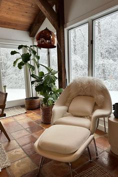 a chair and ottoman in a room with large windows