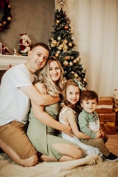 a family poses in front of a christmas tree