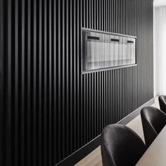 a long table with black chairs in front of a wall that has vertical lines on it