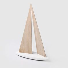 a small wooden sailboat sitting on top of a white surface