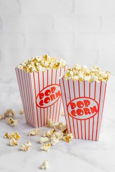 two red and white striped popcorn buckets filled with popcorn