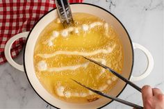 a person is using tongs to stir food in a pan