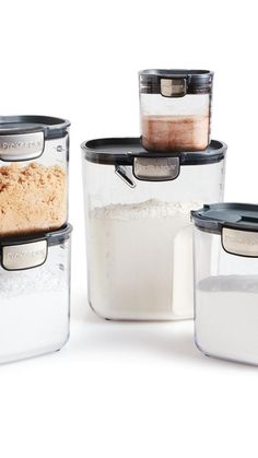 three glass containers with food in them on a white surface, one containing rice and the other containing flour