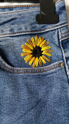 a yellow flower is sticking out of the back pocket of a pair of jeans