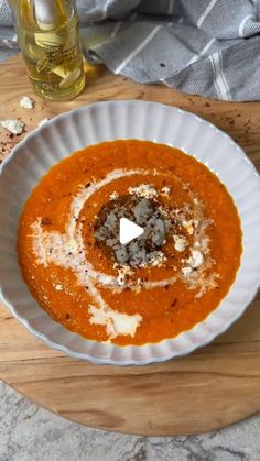 a white bowl filled with soup on top of a wooden cutting board