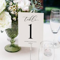 the table numbers are displayed in vases with white flowers and greenery on them