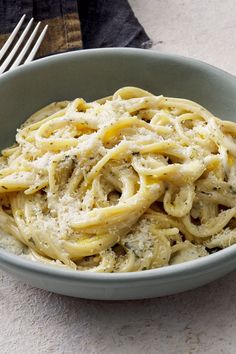 a bowl filled with pasta and cheese on top of a table next to a fork