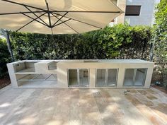 an outdoor bar with glass doors on the outside wall and umbrella over it's top