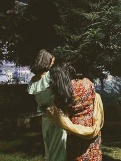 two women hugging each other under a tree