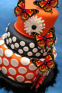 an orange and black cake with butterflies on it