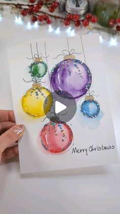 someone holding up a christmas card with ornaments on it