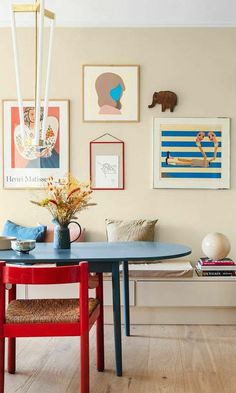 a dining room table and chairs with pictures on the wall above it, in front of a bench